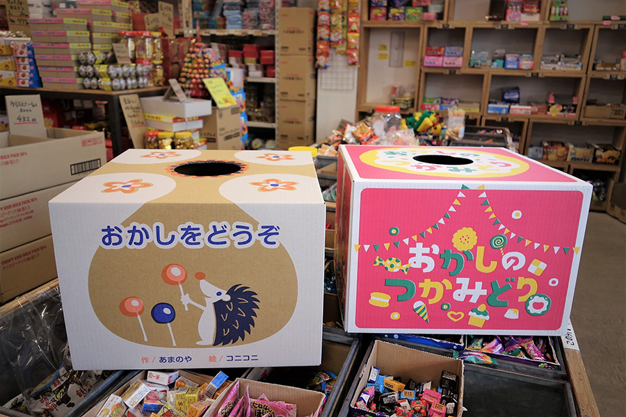 駄菓子のつかみどりBOX、絵本と猫の手が並んでいる