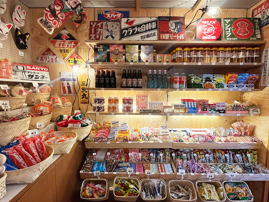 ホテルニューアカオ駄菓子小屋内観、古看板やドリンク、おつまみ駄菓子が並んでいる