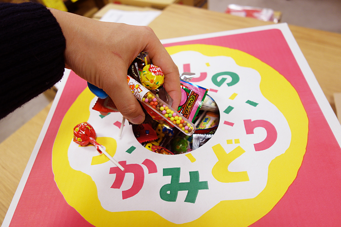 駄菓子のつかみどりBOXの取り出し口から駄菓子をつかみ出している様子