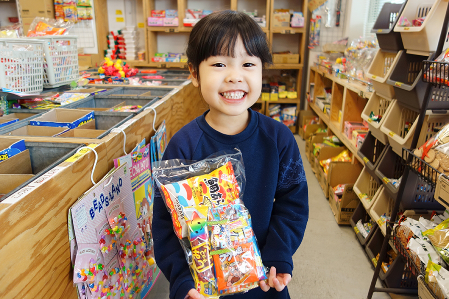 駄菓子の詰め合わせを持って笑顔の子